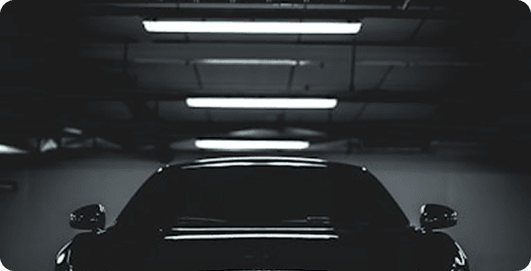 Dark Audi in underground parking garage with fluorescent lighting